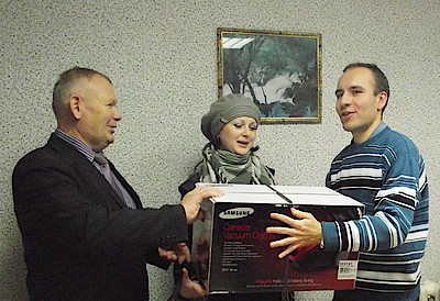 Новости Ливны -М. Соболев (слева) и К. Базаров вручают пылесос Ю. Захаровой.